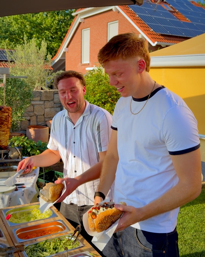 Marc und Lukas lachen an der ALMANS Station und bauen Döner